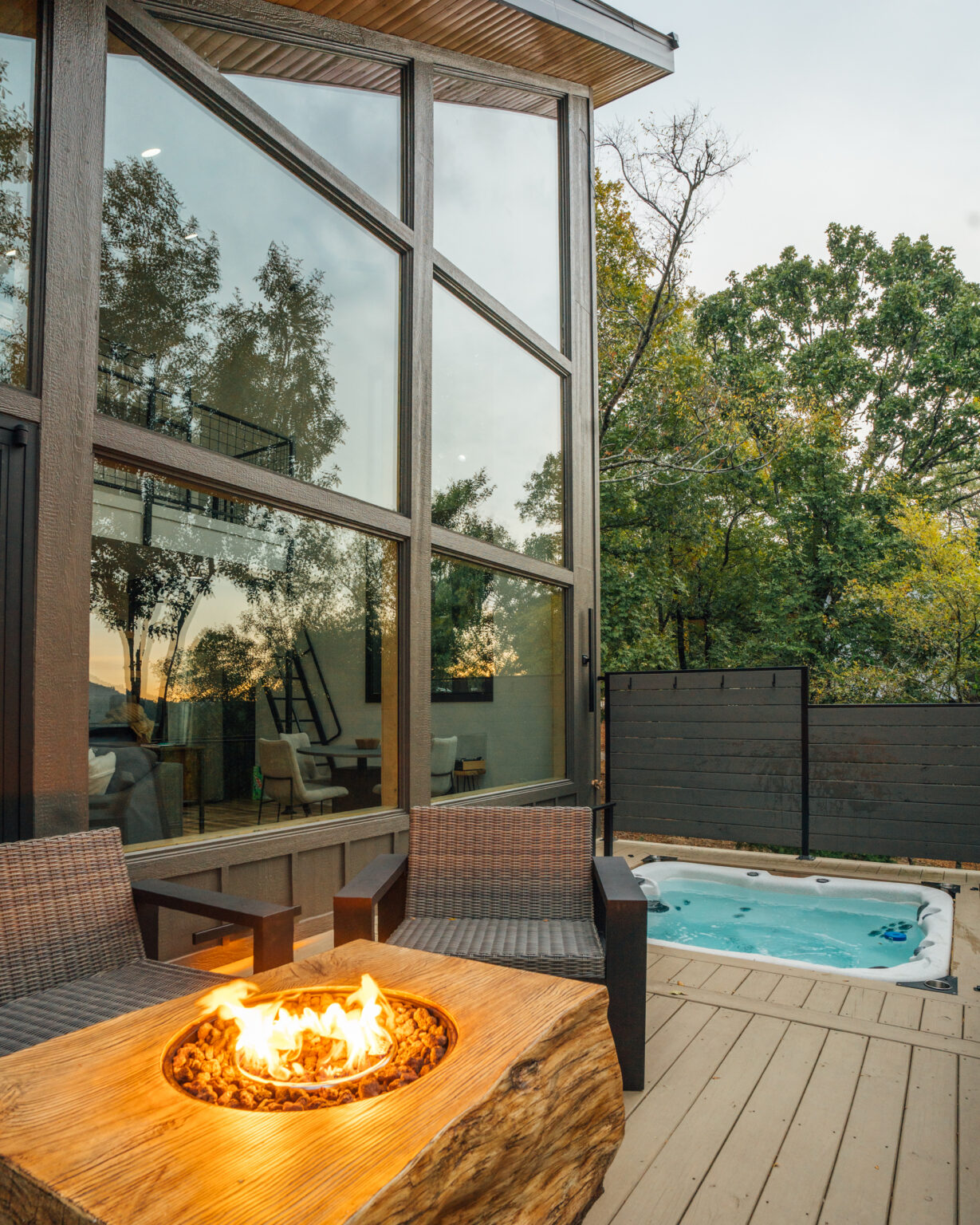 Fire table and hot tub on a treehouse deck at dusk