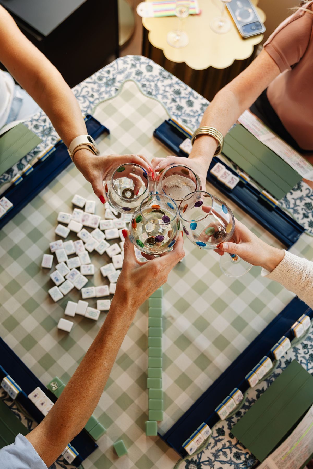 Four friends toasting over a mahjong table
