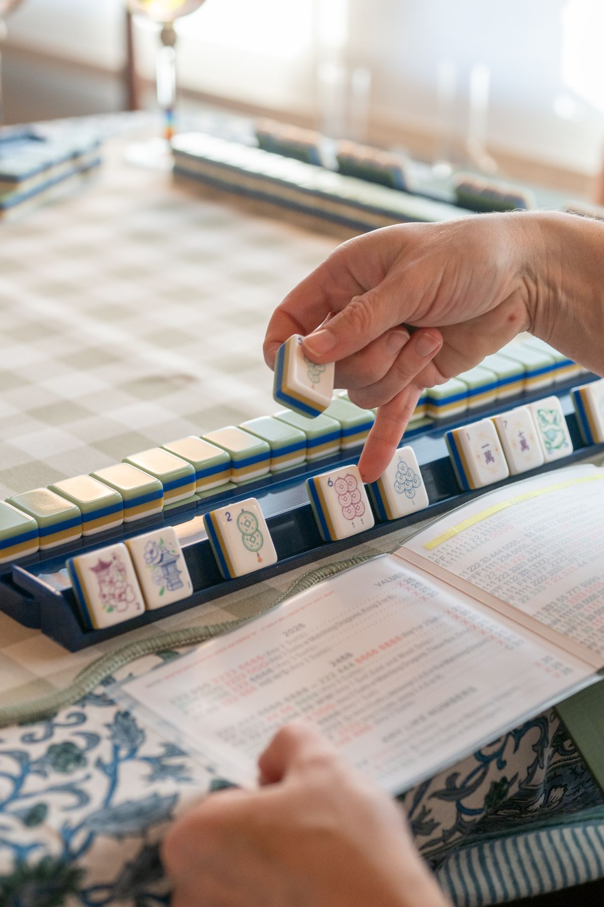 A hand places a tile on the rack beside the card